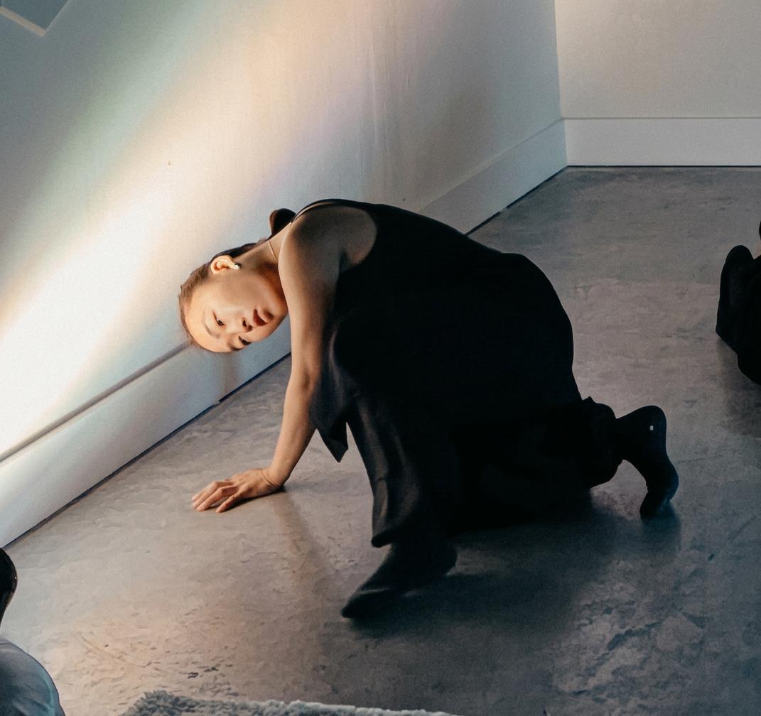 Dancer resting against the cyclorama wall in soft daylight