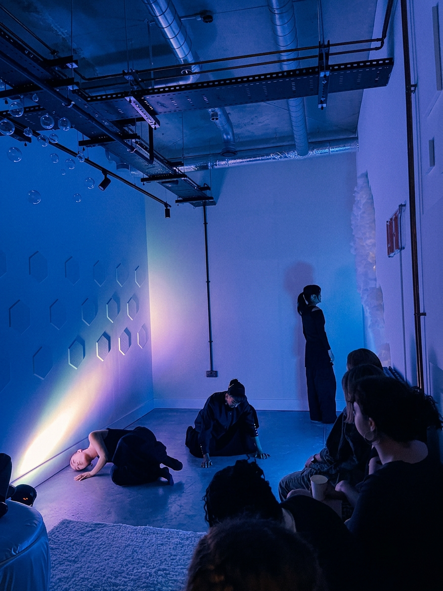 Performers in black on the cyclorama floor under cool blue light